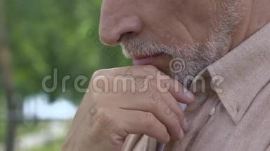 一个人坐在长凳上思考着生活，令老人心烦意乱，摸着他的脸